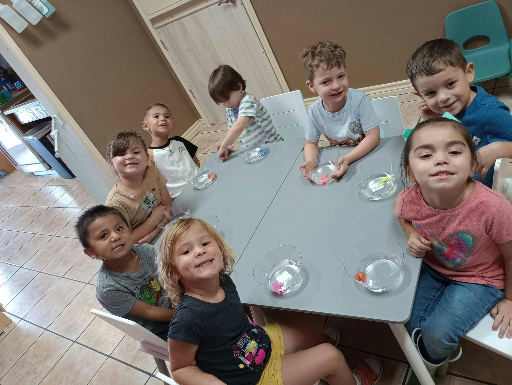Group of children sitting around a table with small clear bowls