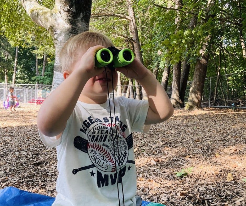 Child looking through green binoculars outdoors