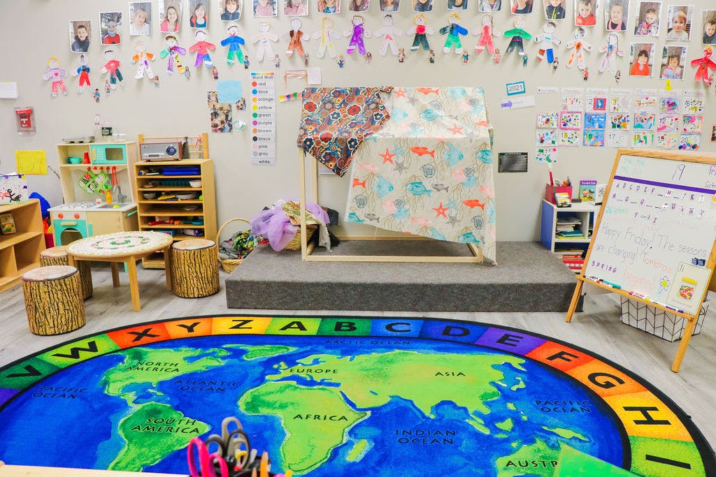 Classroom with a world map rug, small table, and play area