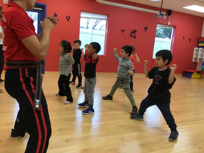 Adult teaching children martial arts in a studio
