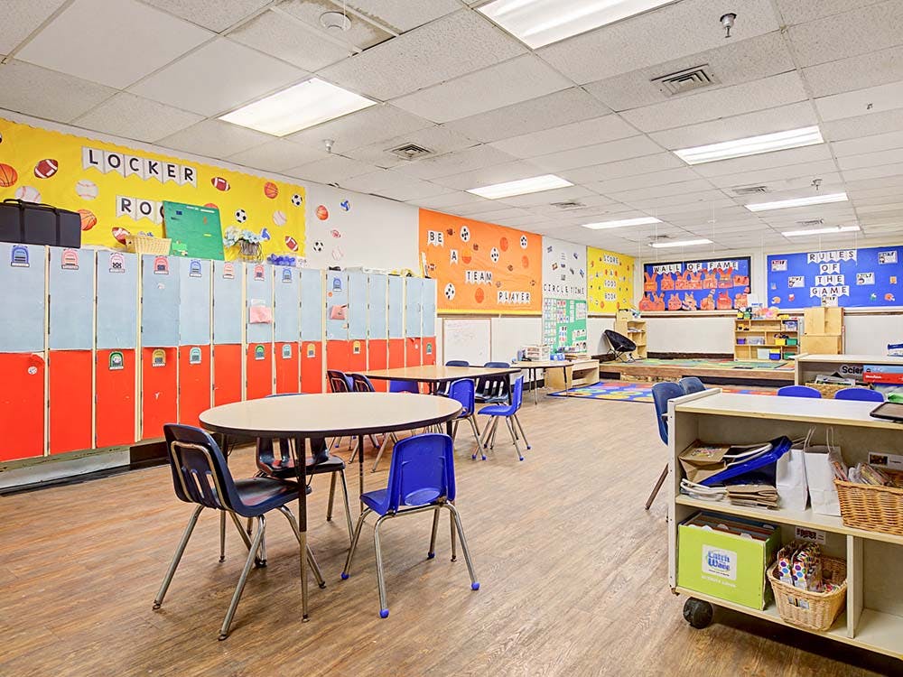 Classroom with small tables and chairs, lockers, and colorful decorated walls