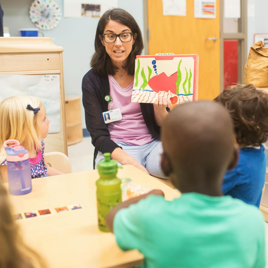 Person showing children a drawing in a classroom