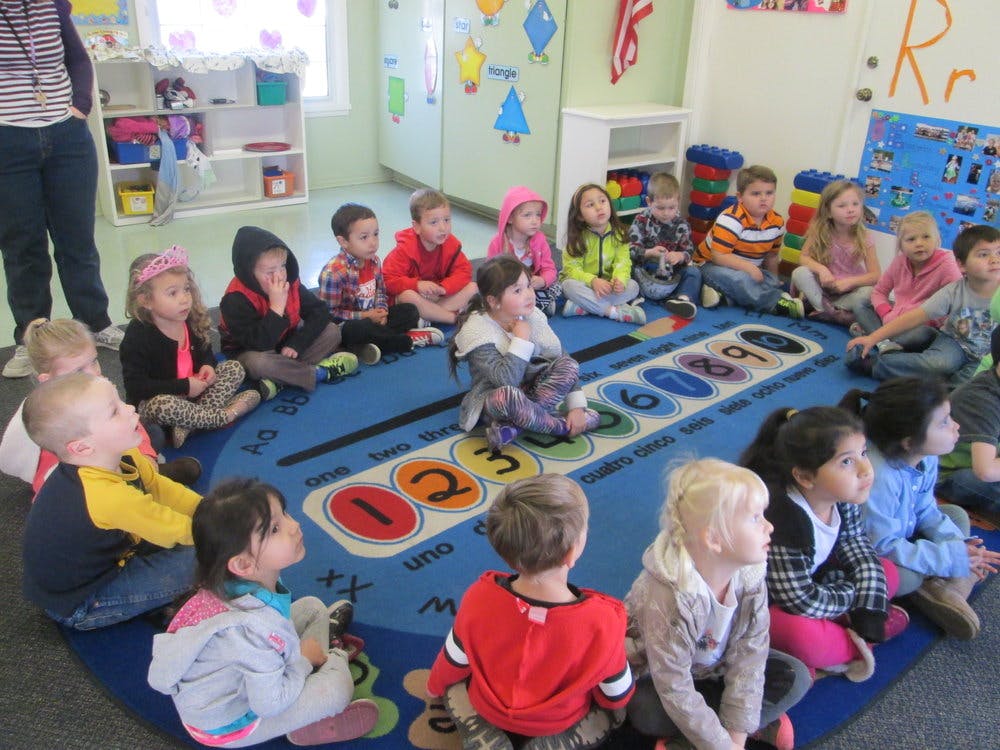 Children sitting on a rug in a classroom