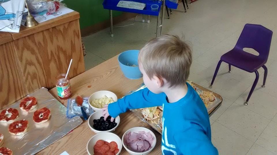 Child reaching for ingredients in bowls on a table