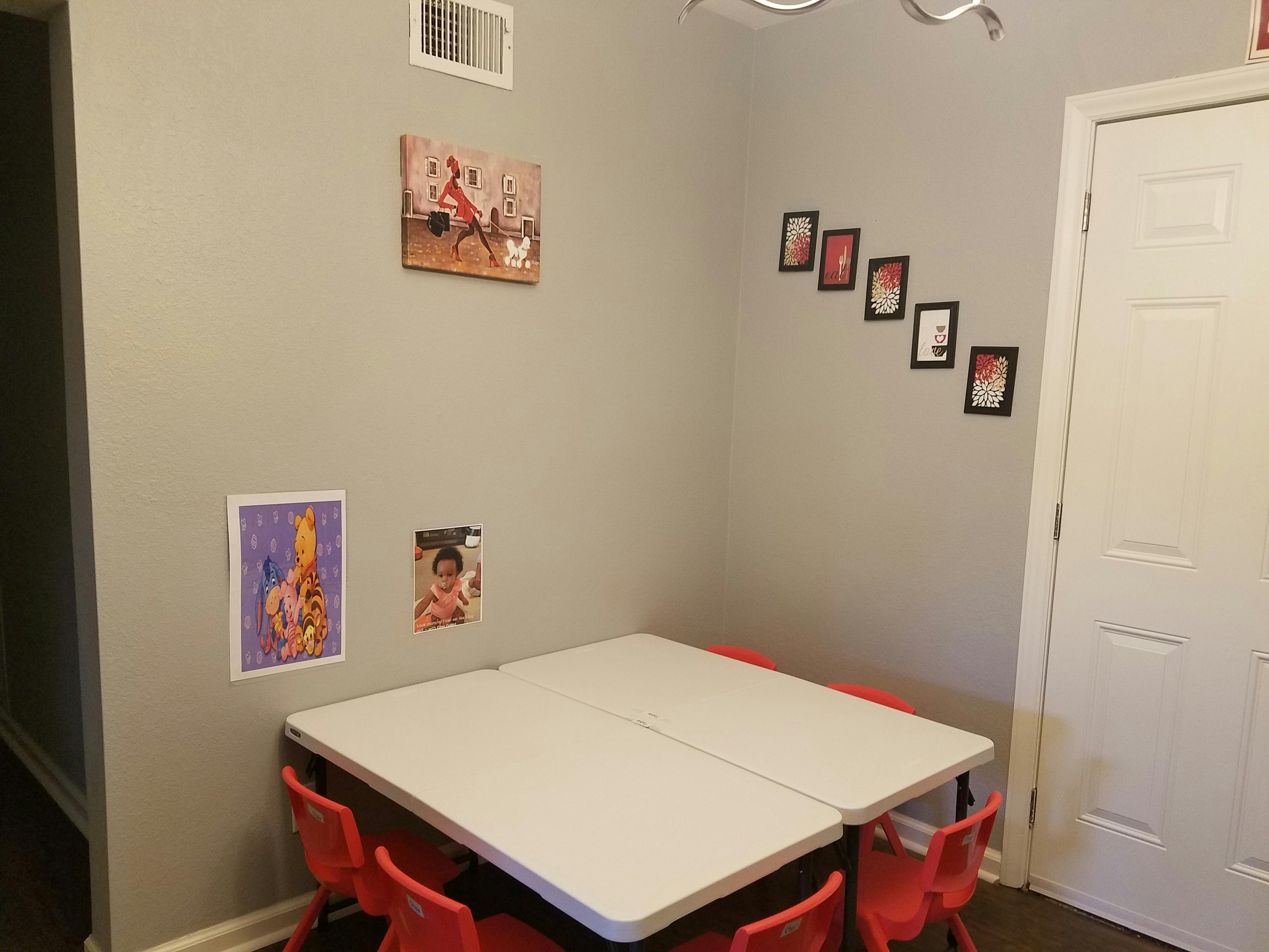 Two tables with red chairs in a room with pictures on the wall