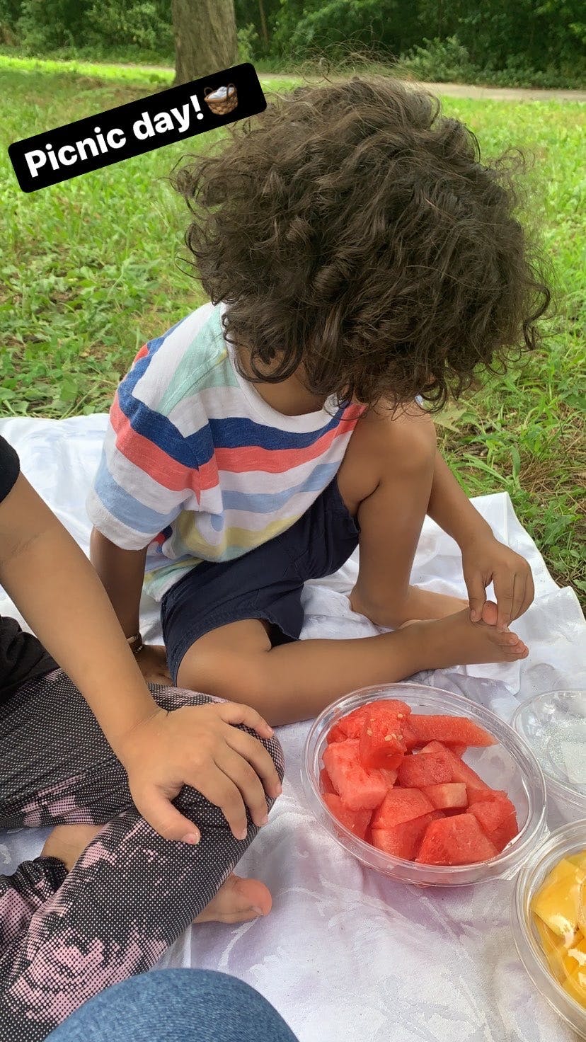 Child sitting on a blanket with a bowl of watermelon, text says "Picnic day!"