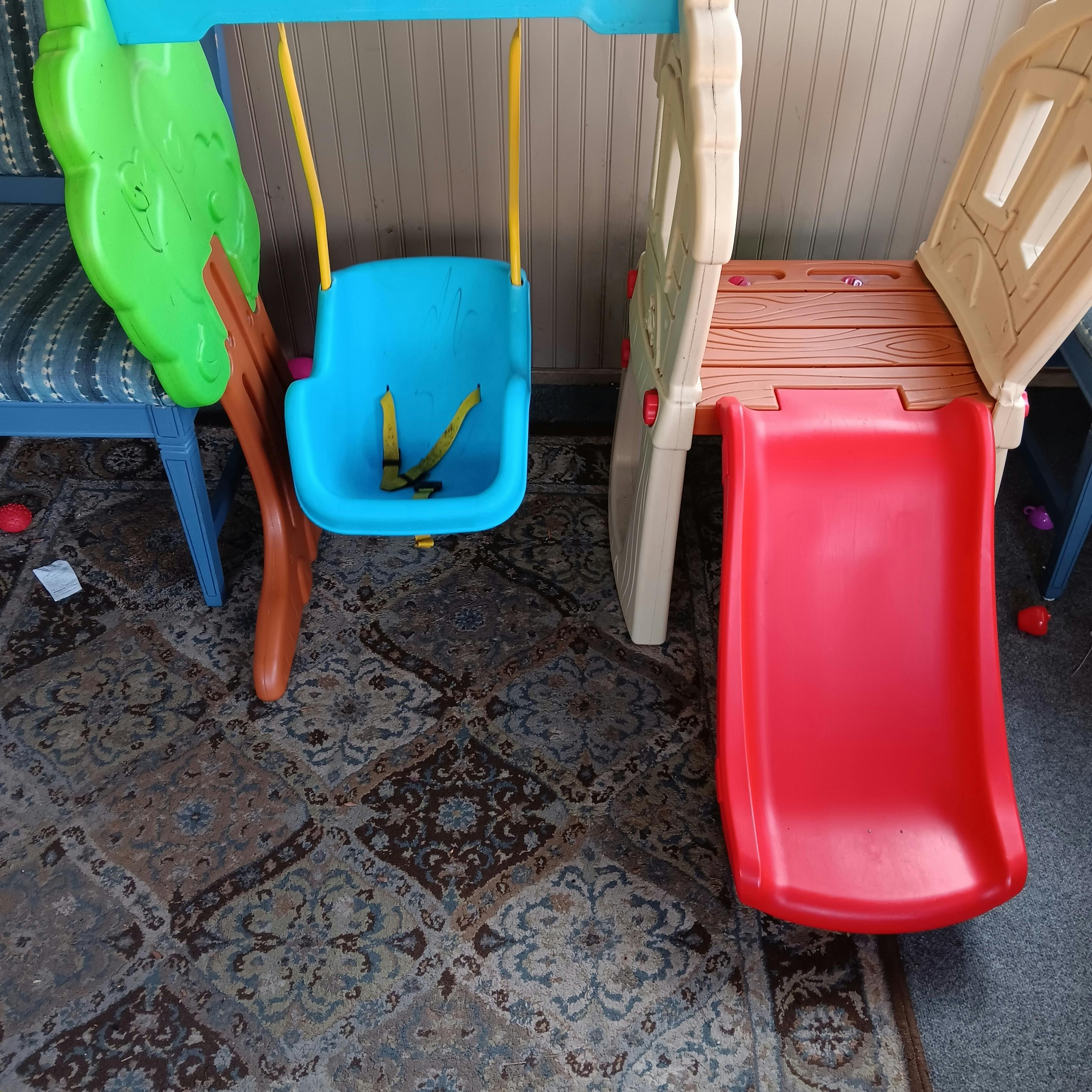 Children's play set with a blue swing and a red slide