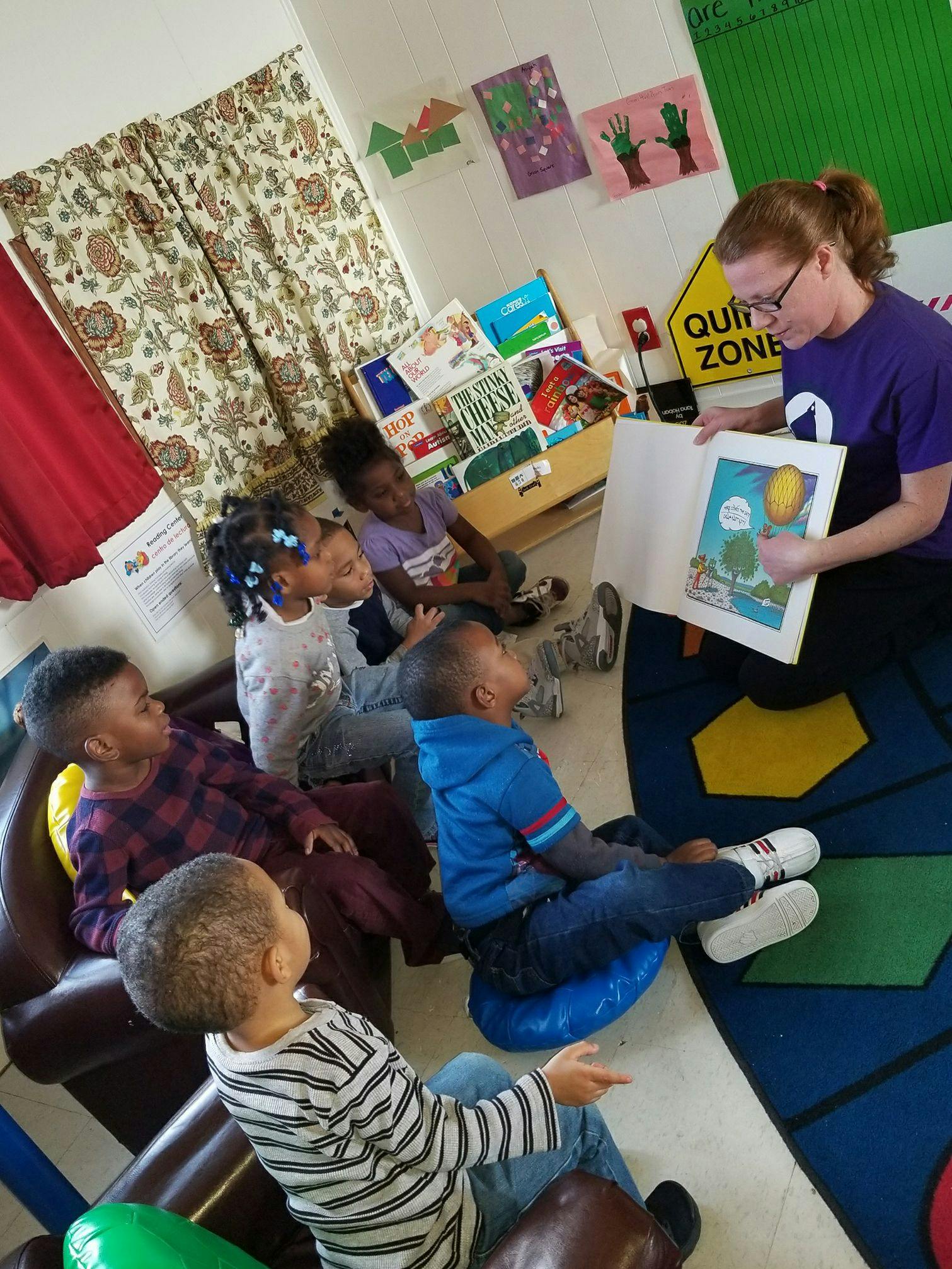 Person reading a book to a group of children