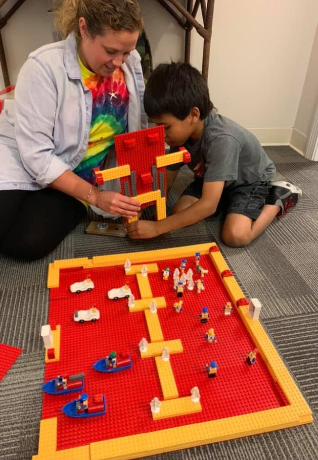 Person and child building with colorful blocks on the floor