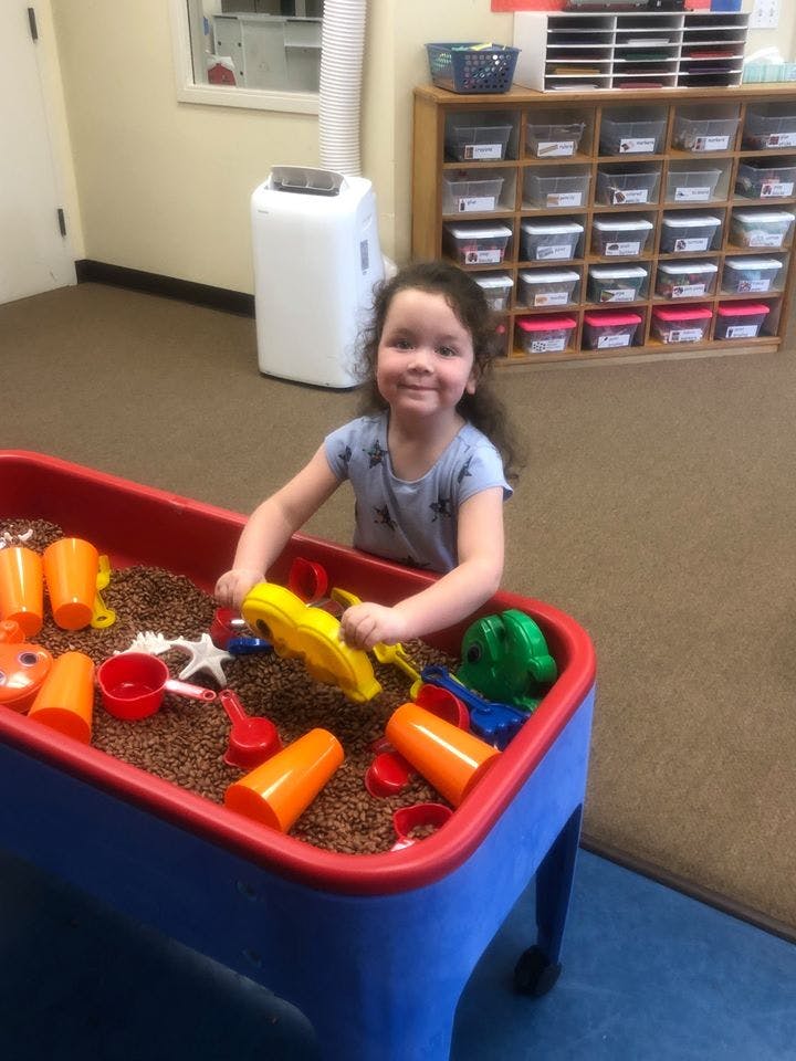 Child playing in a sensory bin with scoops and cups
