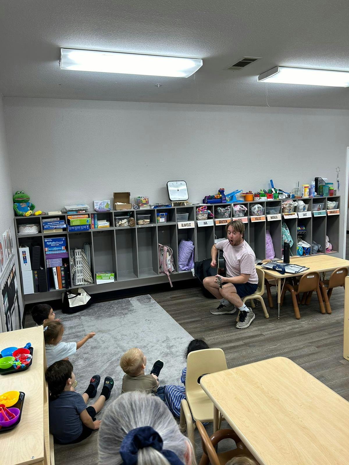 Adult sitting on a chair with children sitting on the floor in a classroom