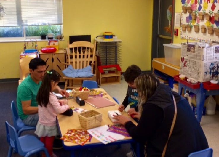 Adults and children sitting at a table in a classroom