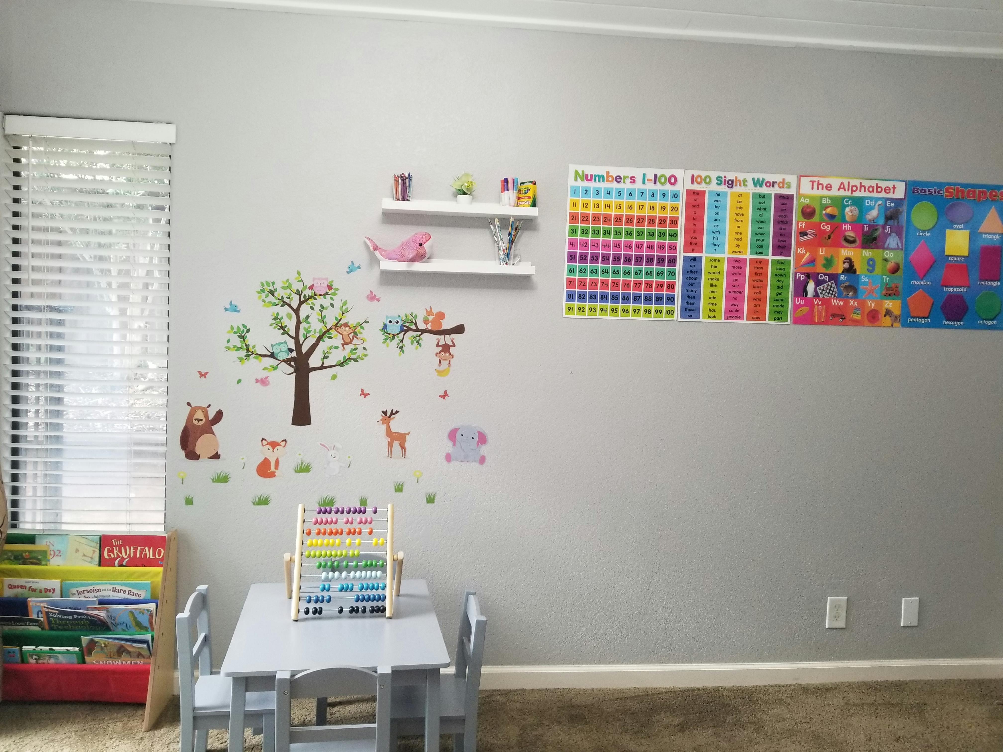 Children's play area with wall decals, educational posters, and small table