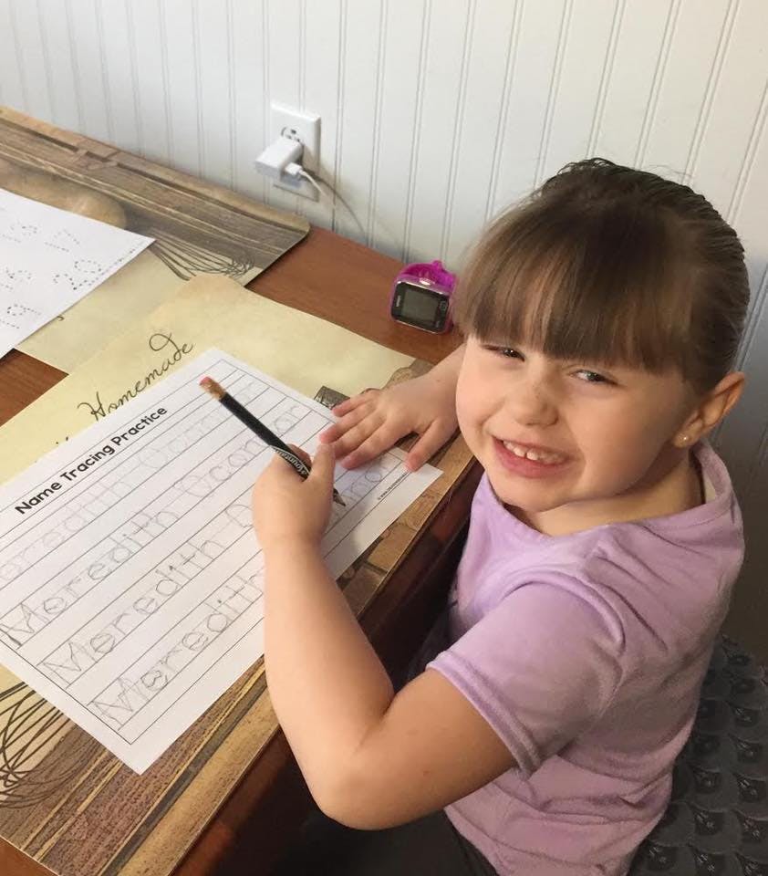 Child writing on a "Name Tracing Practice" worksheet