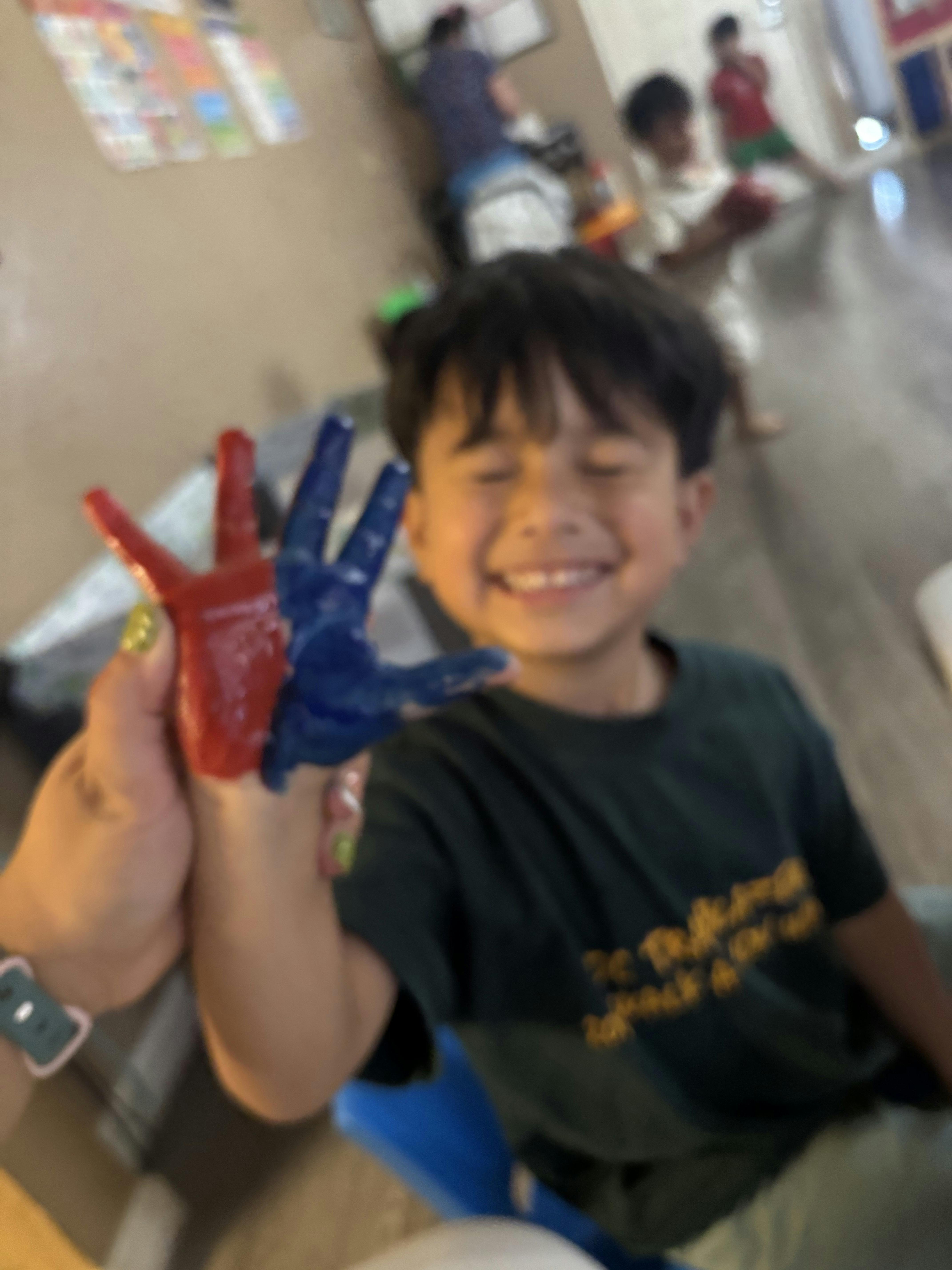 Child with red and blue paint on hands