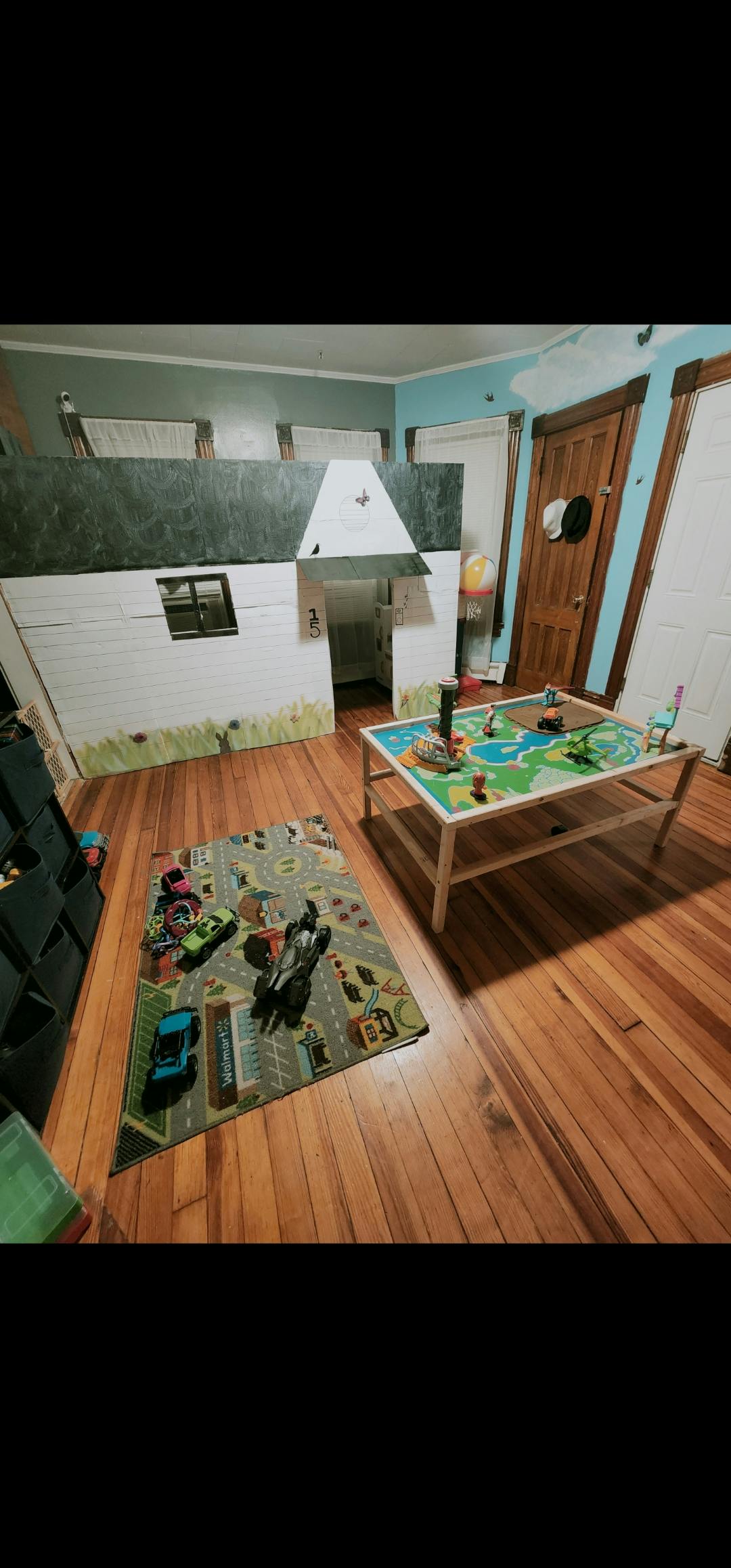 Playroom with a playhouse, activity table, and rug with toy cars