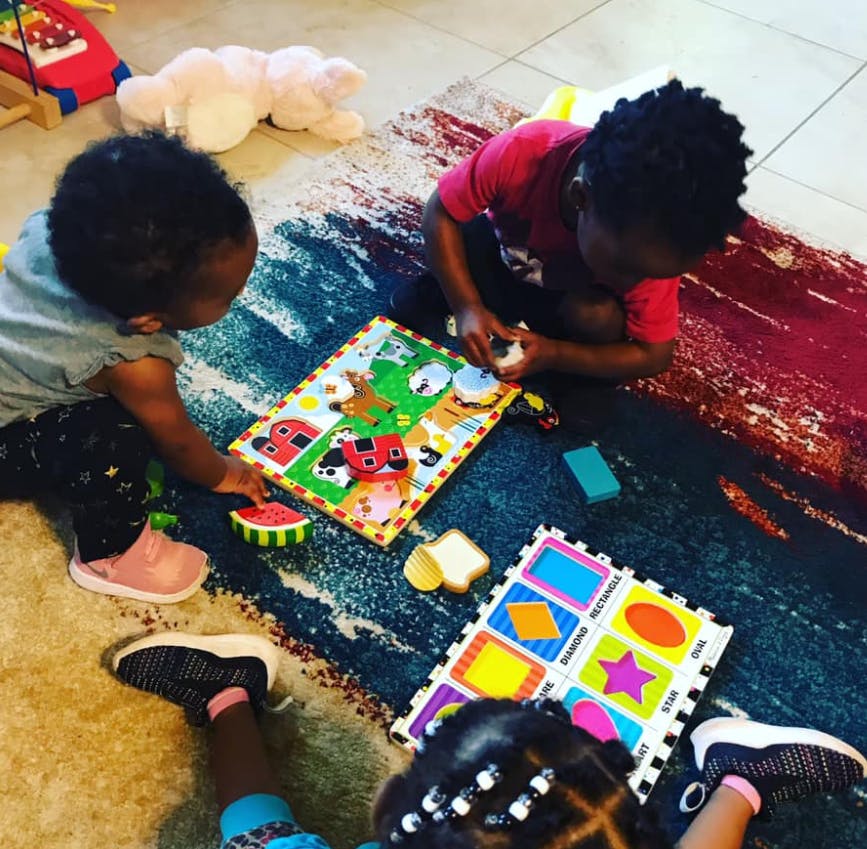 Three children playing with puzzles on a rug