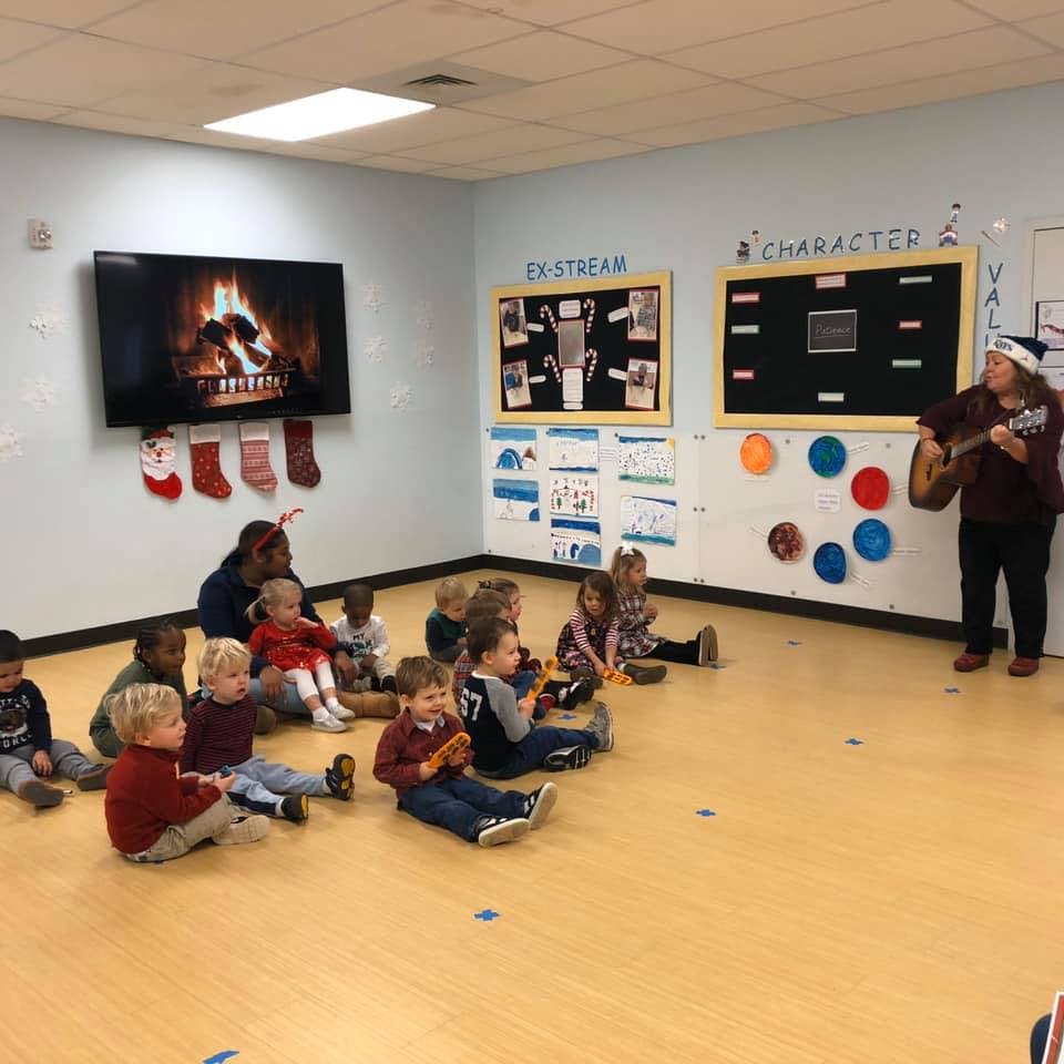 Person playing guitar for children sitting on the floor in a classroom