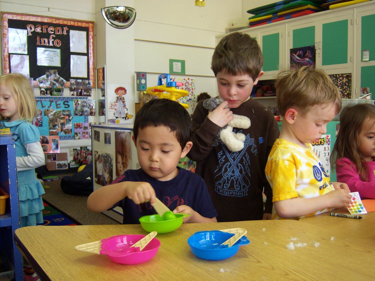Children at a table with colorful bowls and craft sticks