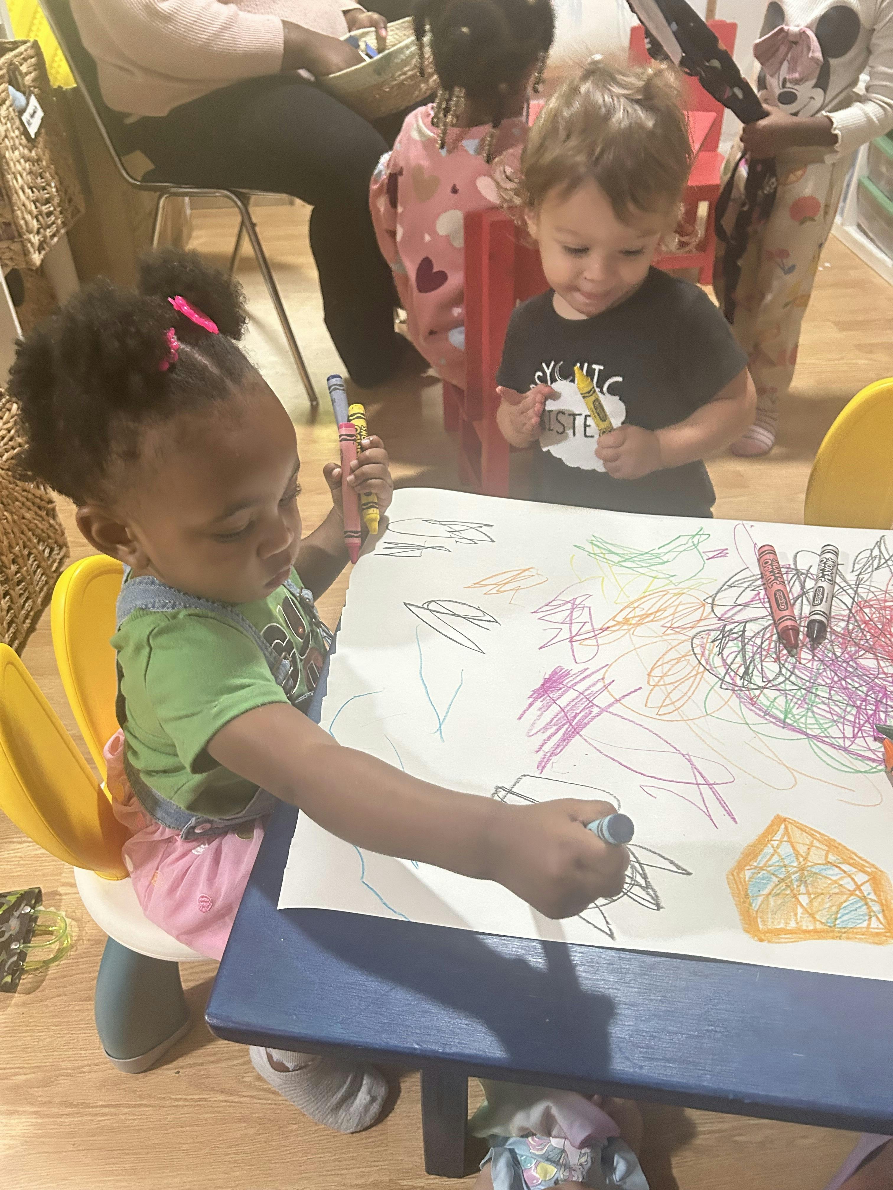 Children drawing with crayons on paper at a table