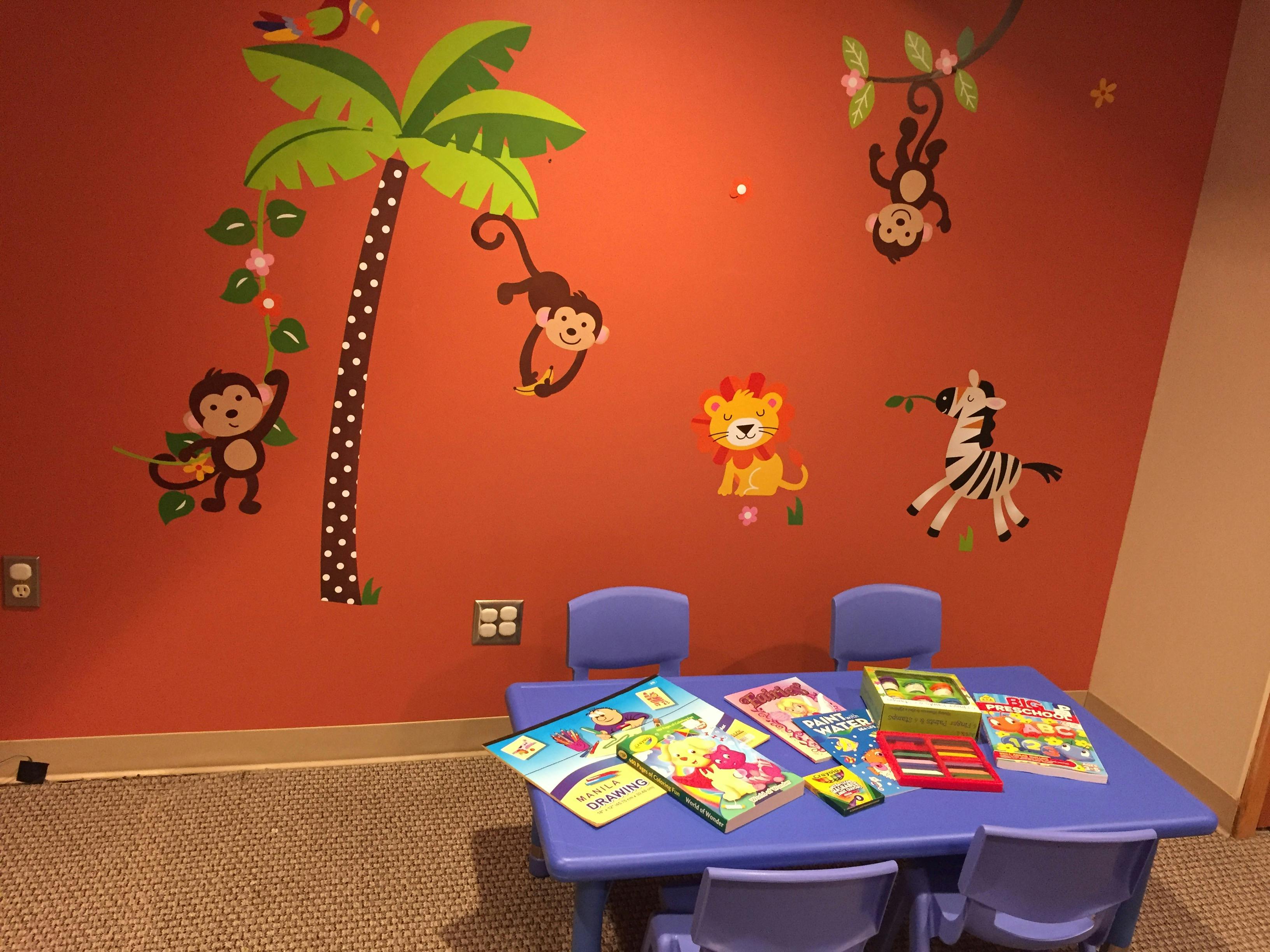 Children's play area with animal wall decals and a table with books