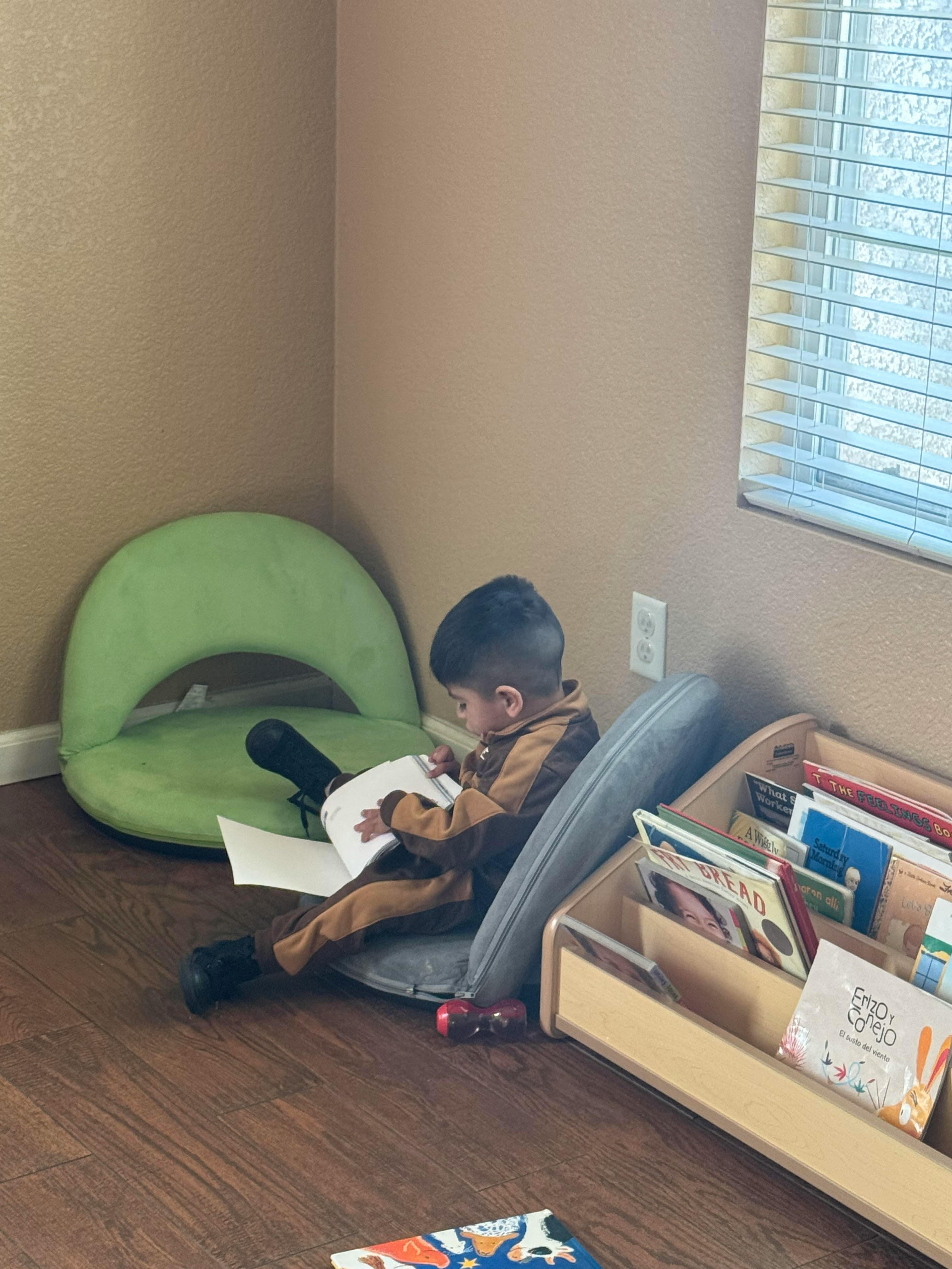 Child sitting on floor reading a book next to a bookshelf