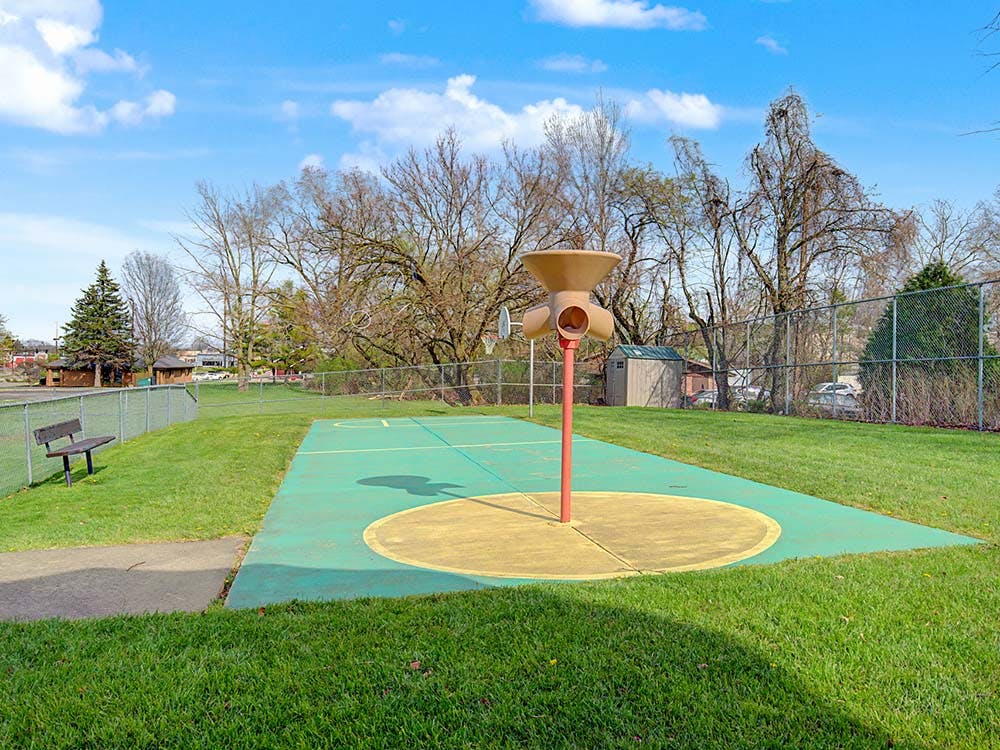 Playground area with a painted green court and a unique play structure