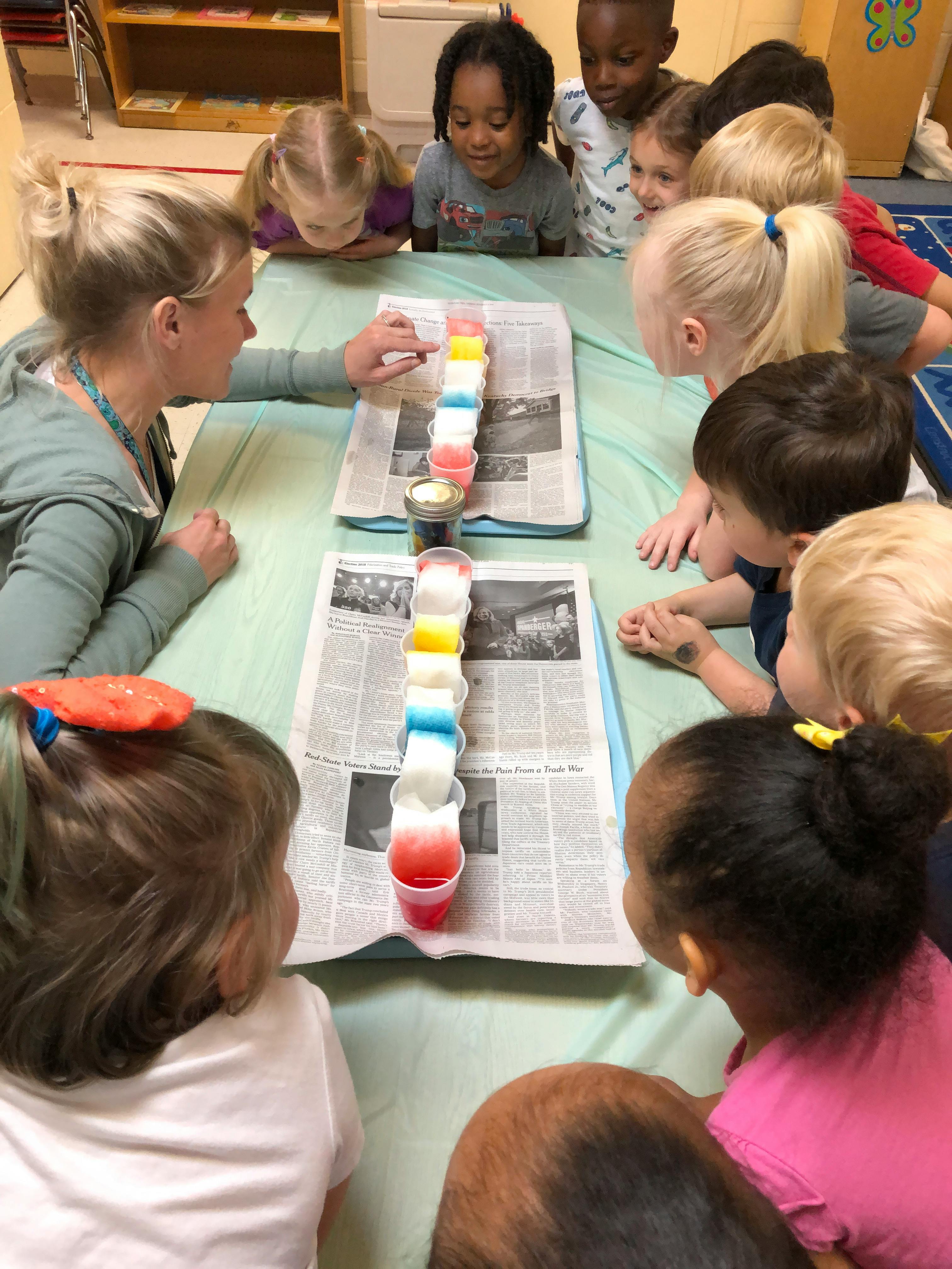 Adult and children gathered around a table watching a science experiment