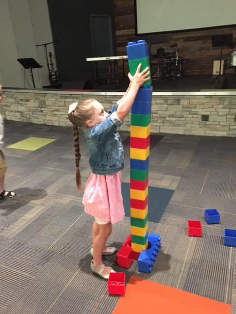 Child building a tall tower with large colorful blocks