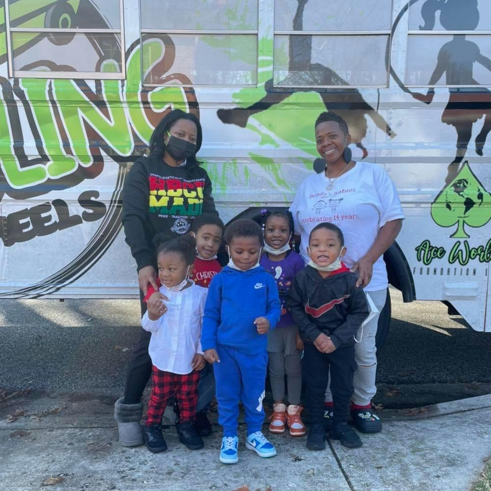 Two adults and five children standing in front of a vehicle with text