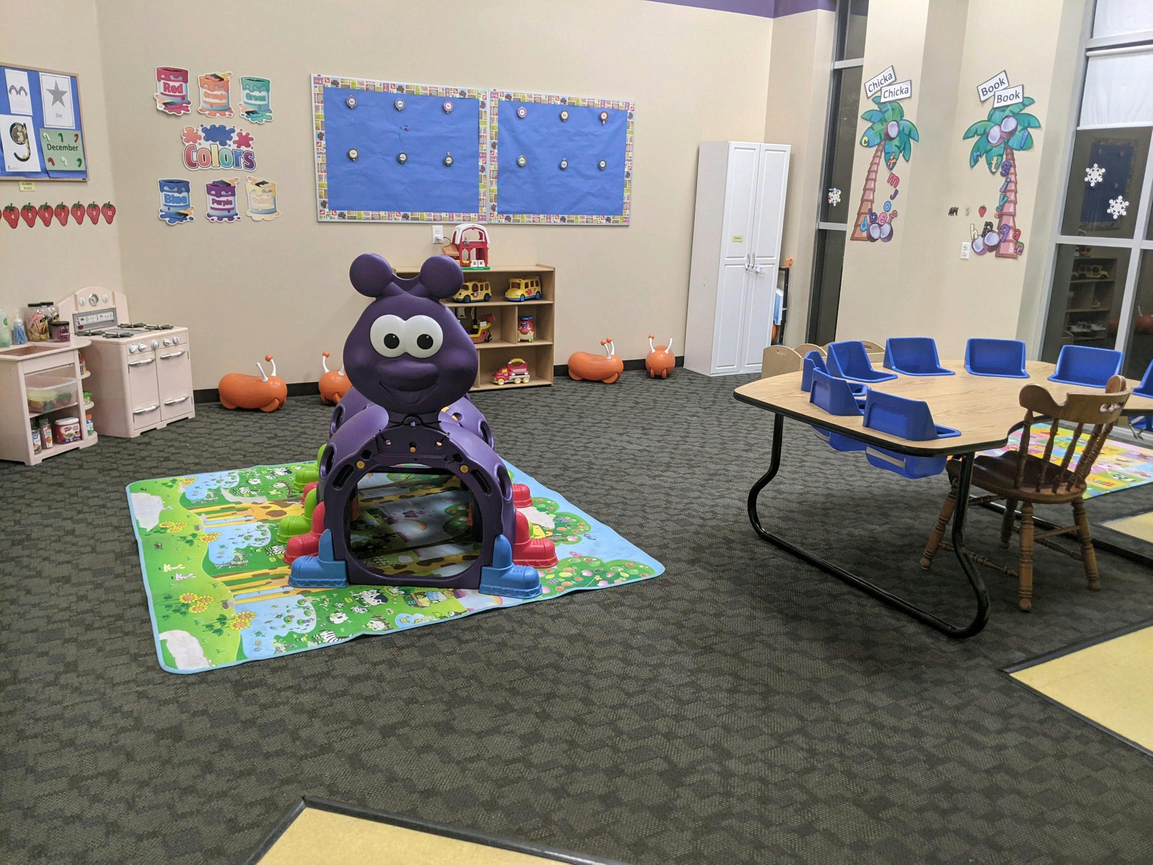 Playroom with a purple caterpillar toy and a table with blue chairs