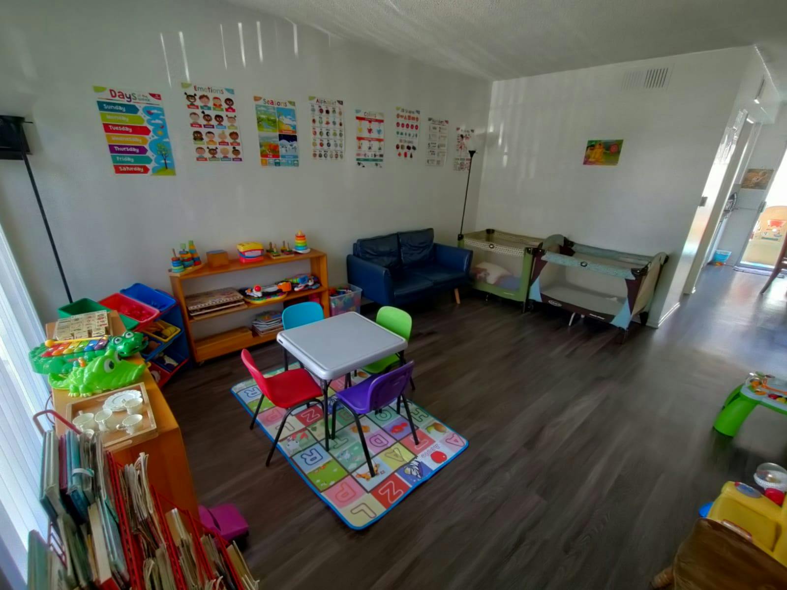 Children's play area with small table and chairs, shelves of toys, and cribs