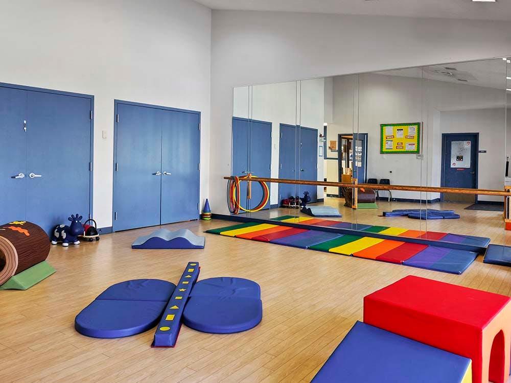 Playroom with colorful mats, soft play equipment, and a mirror wall