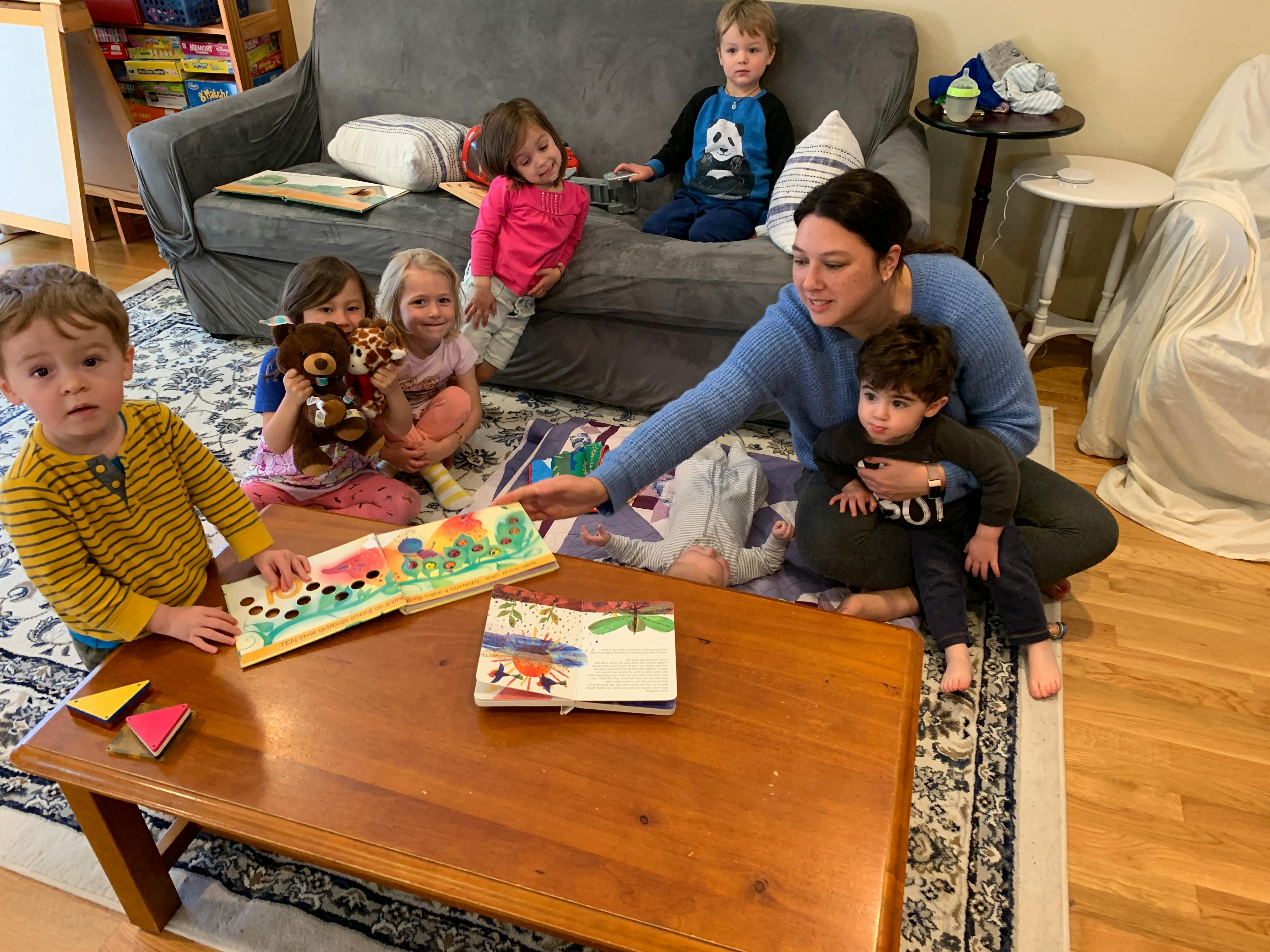 Adult and children reading books on the floor