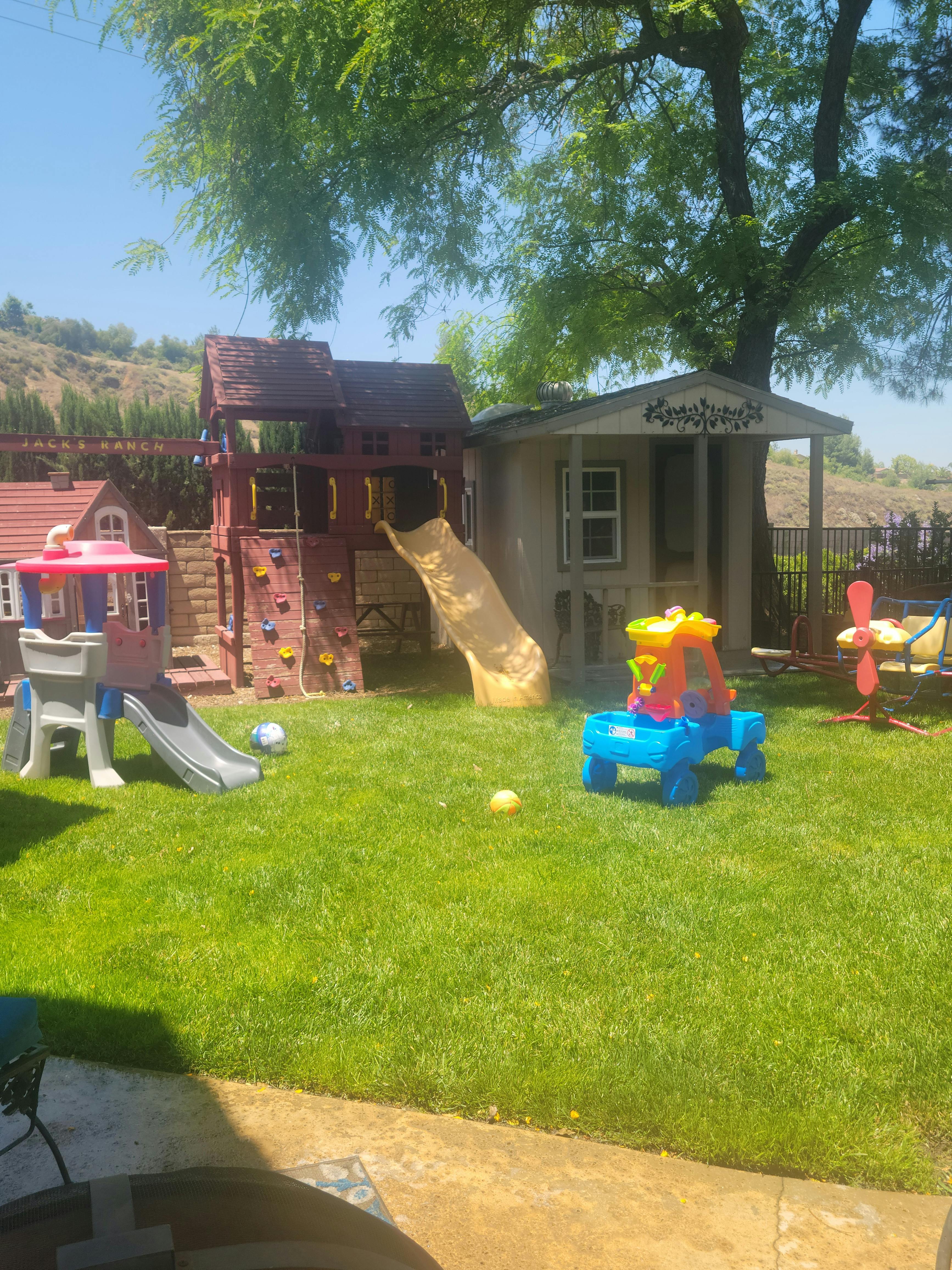 Backyard with a playset, slide, and playhouse
