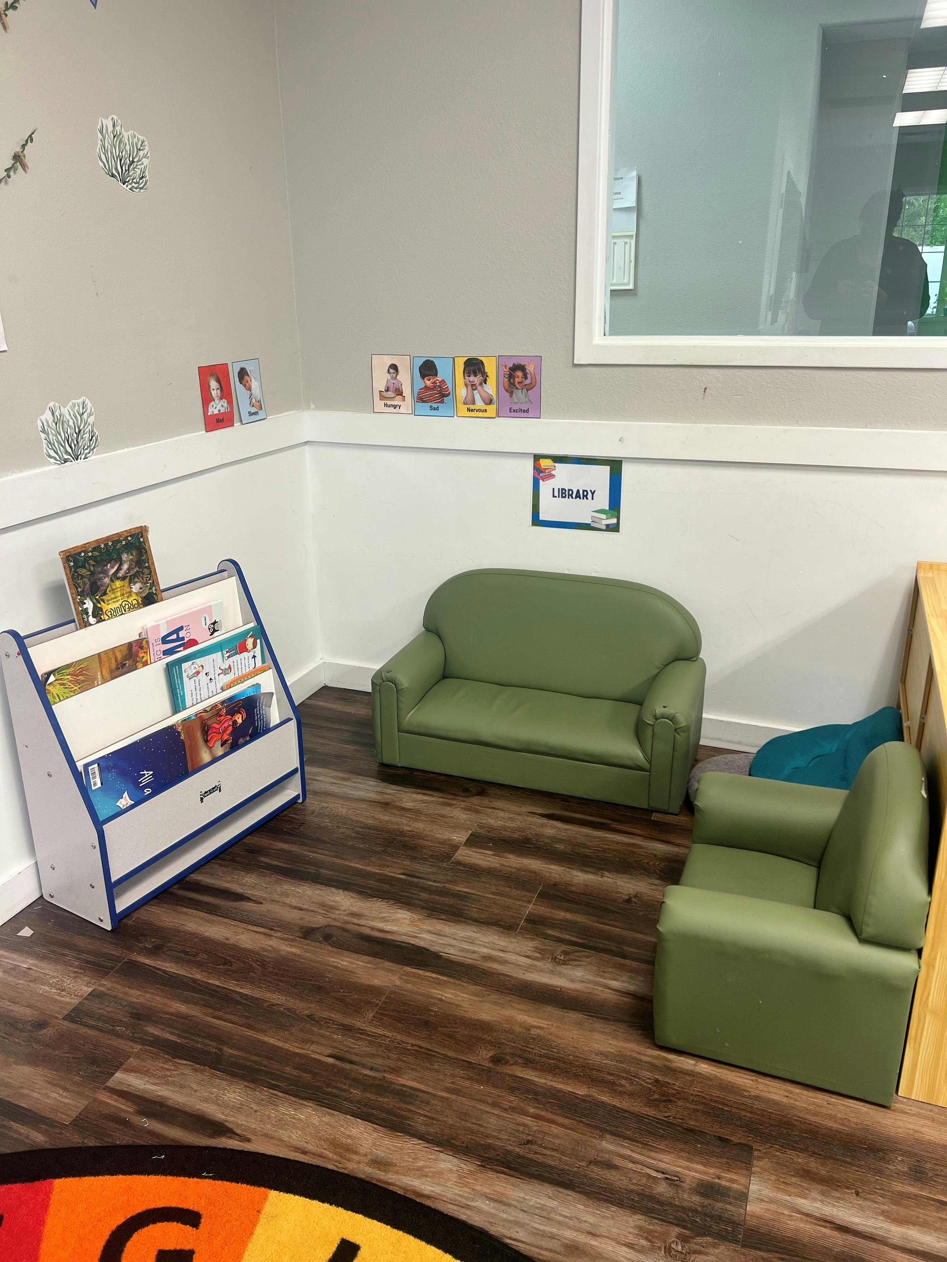 Small library corner for children with a bookshelf and green lounge furniture