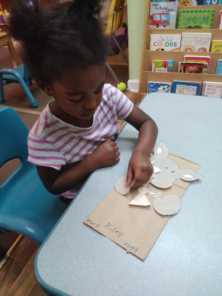 Child assembling a craft project on a table
