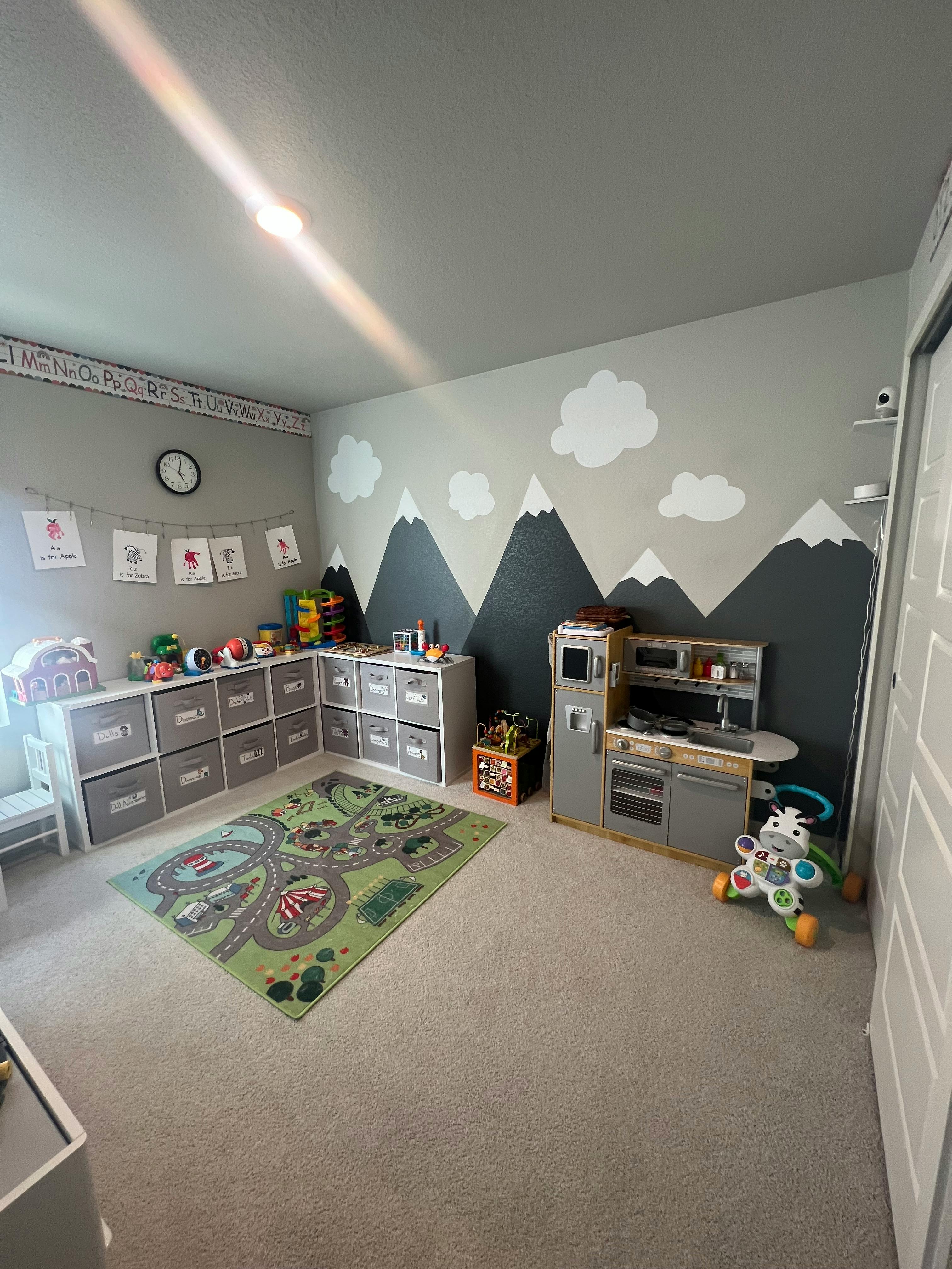 Playroom with mountain mural, toy kitchen, storage units, and playmat