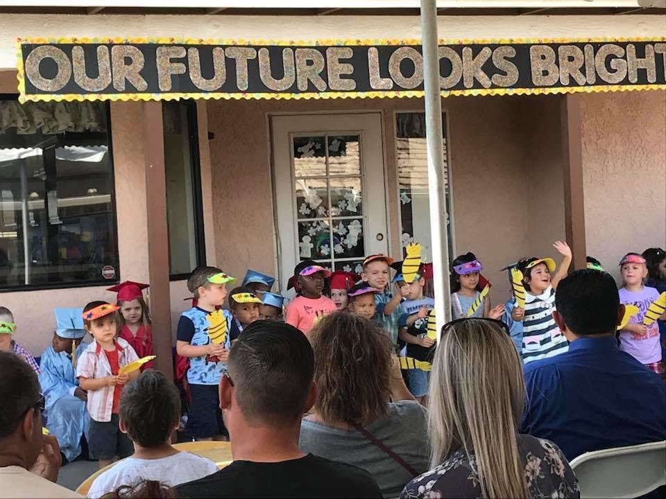Children performing in front of adults with a sign that reads "OUR FUTURE LOOKS BRIGHT"