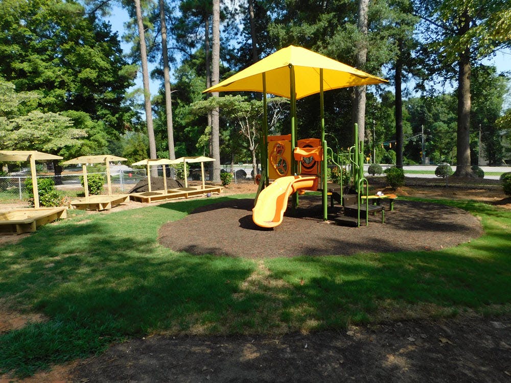 Playground with yellow slide and umbrella, sandboxes in background