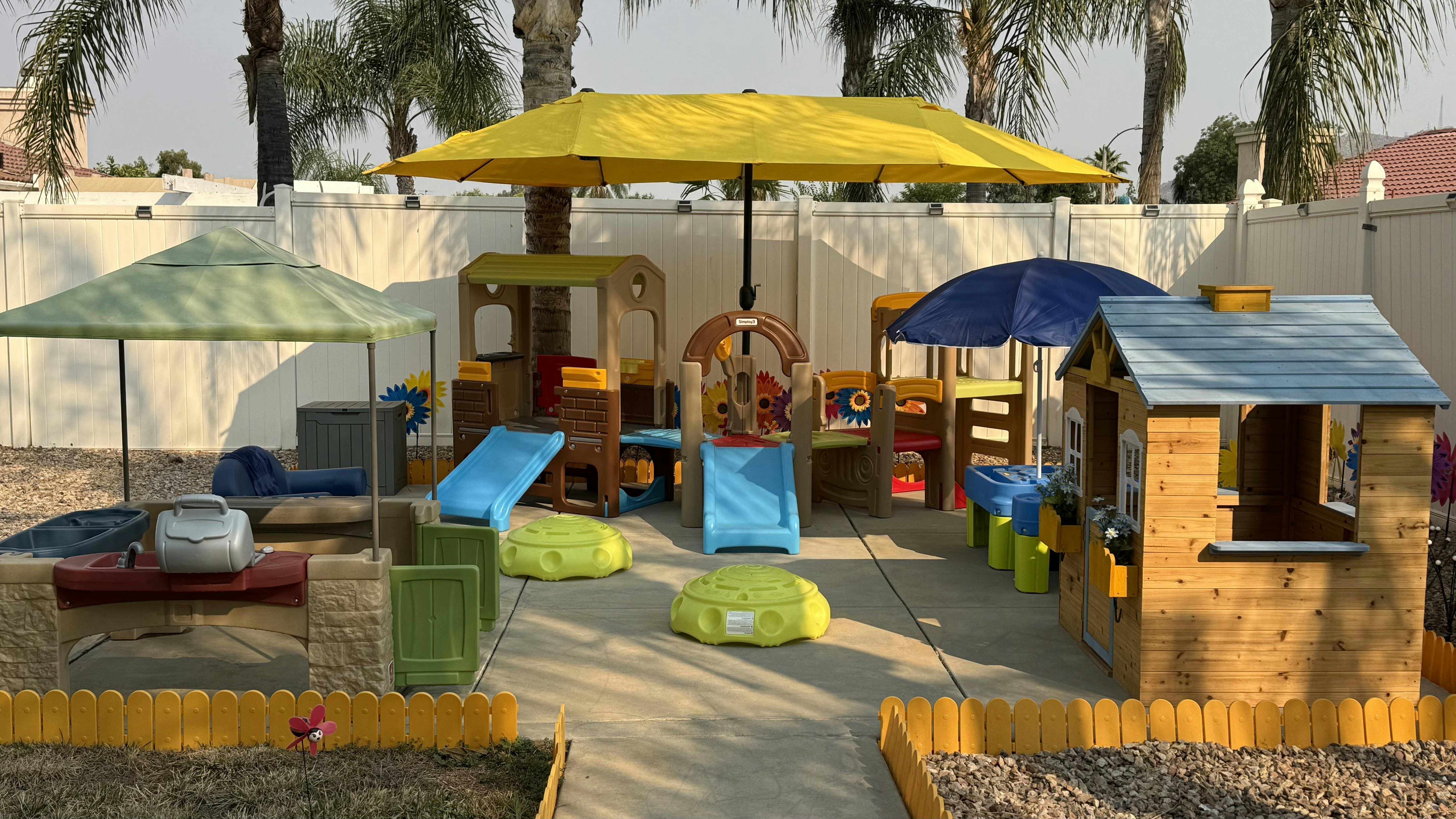 Outdoor play area with slides, playhouses, and umbrellas