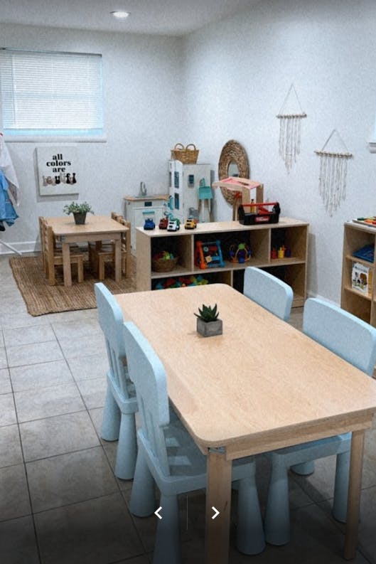 Classroom with small tables and chairs, shelves with toys