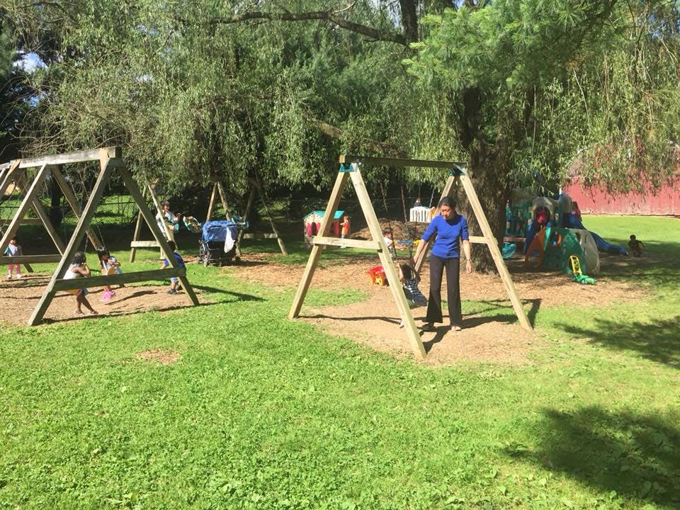 Person standing near a swing set in a playground