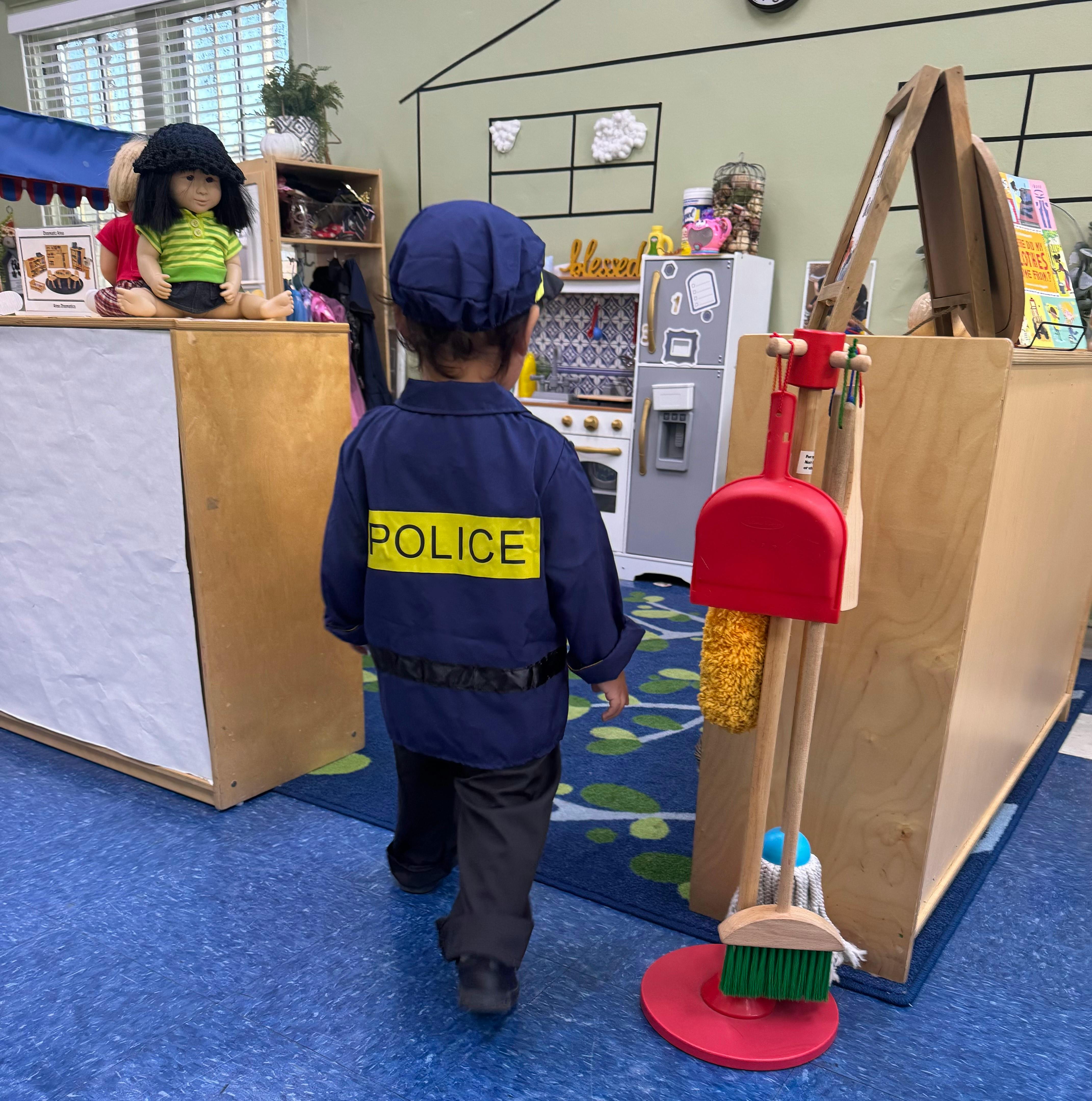 Child in a police costume walking in a classroom