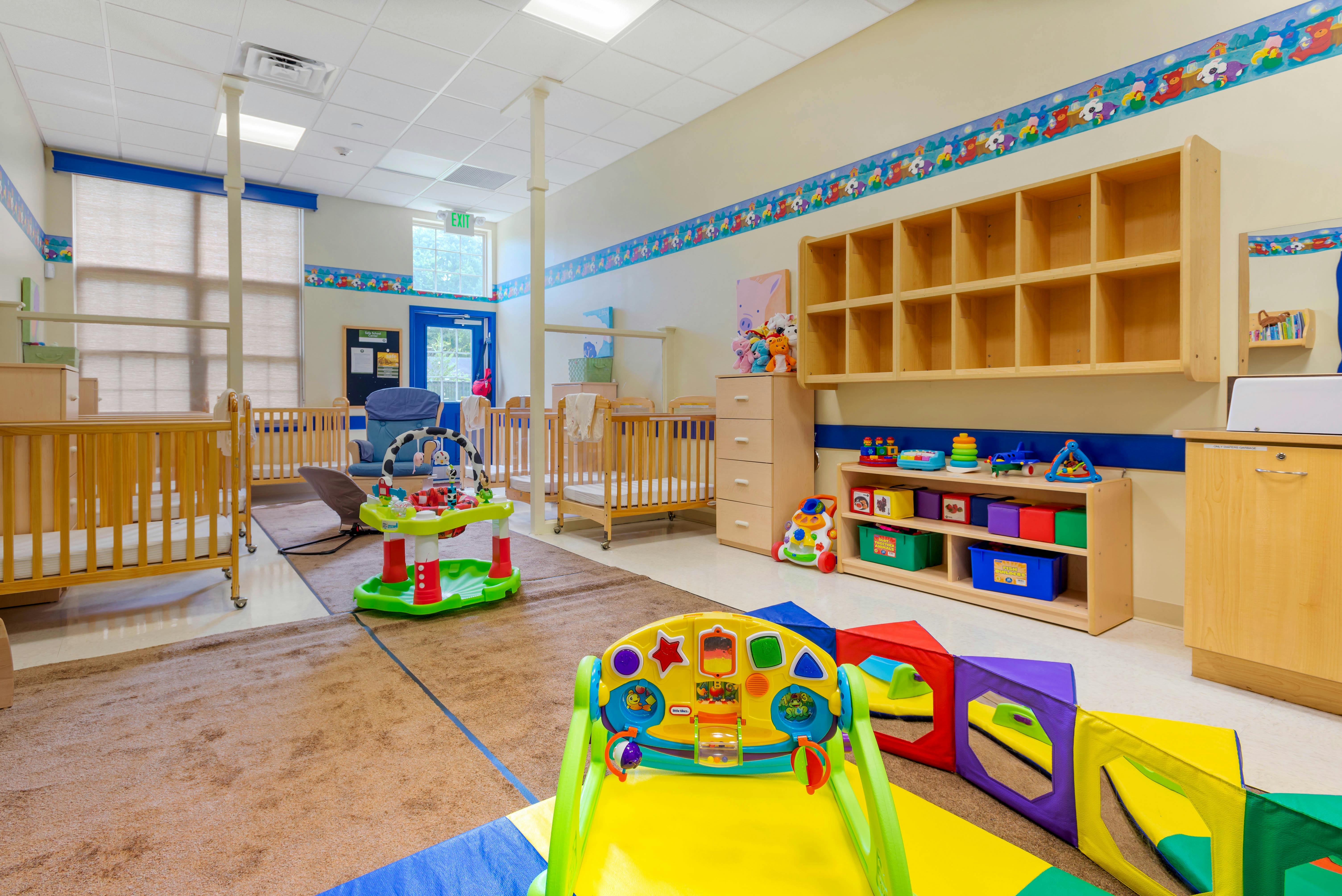 Cribs, infant toys, and child-sized furniture in a bright room