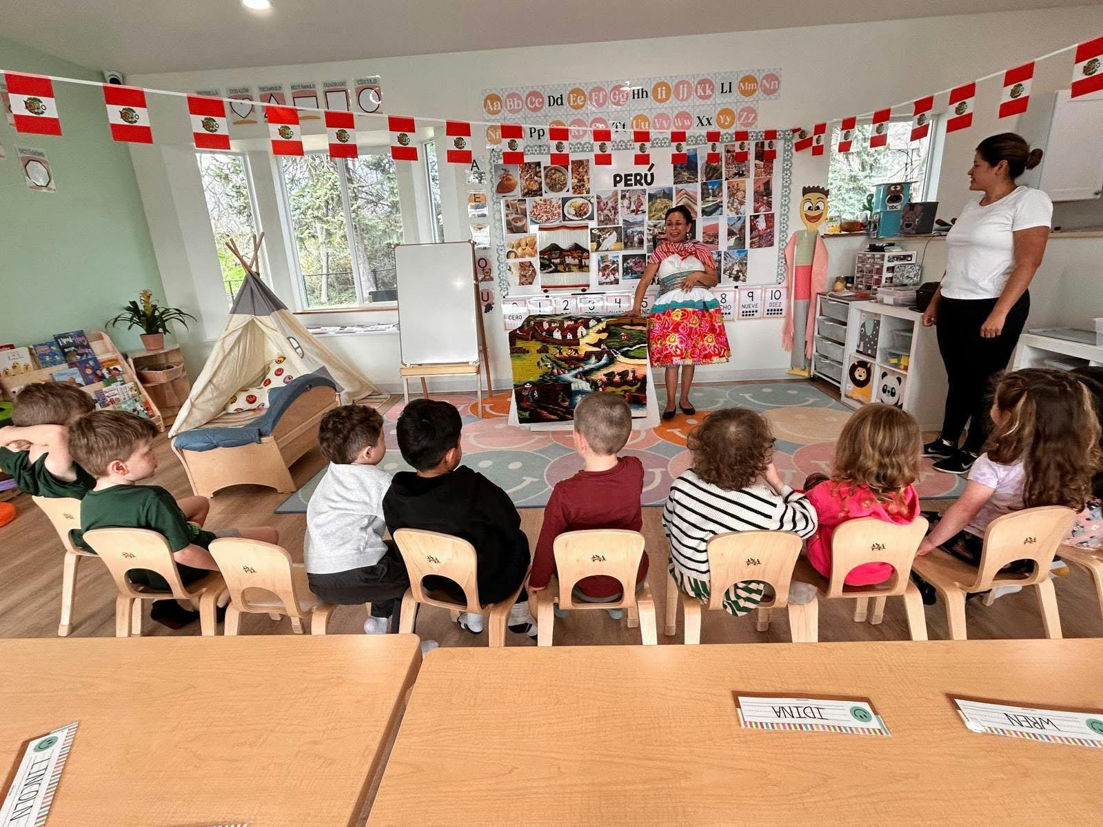 Adults teaching children in a classroom decorated with flags