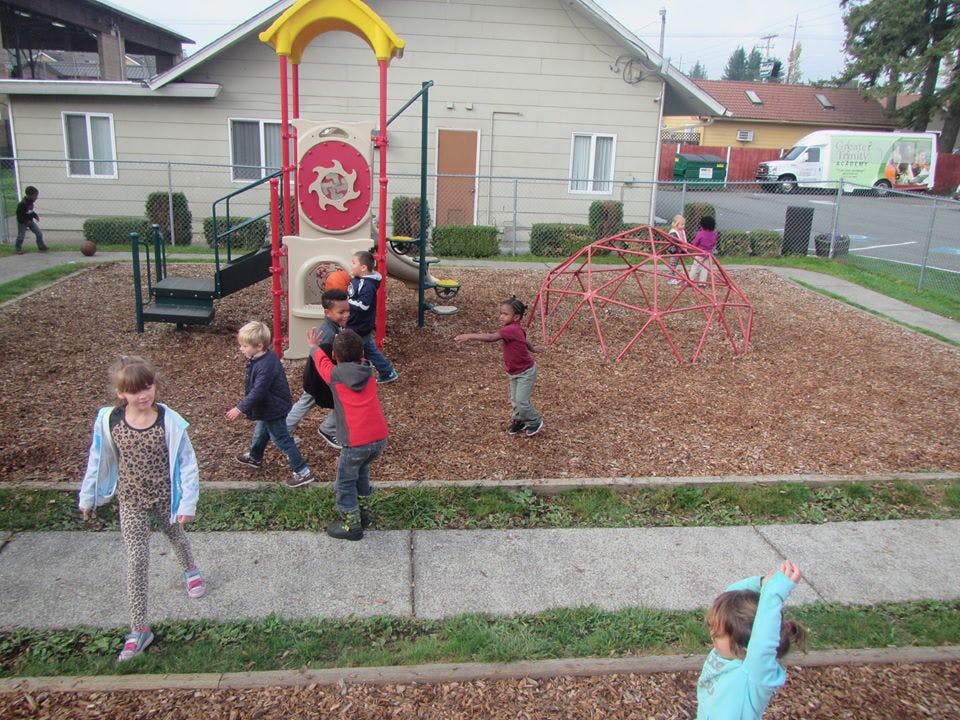 Children playing on a playground with wood chips and play structures