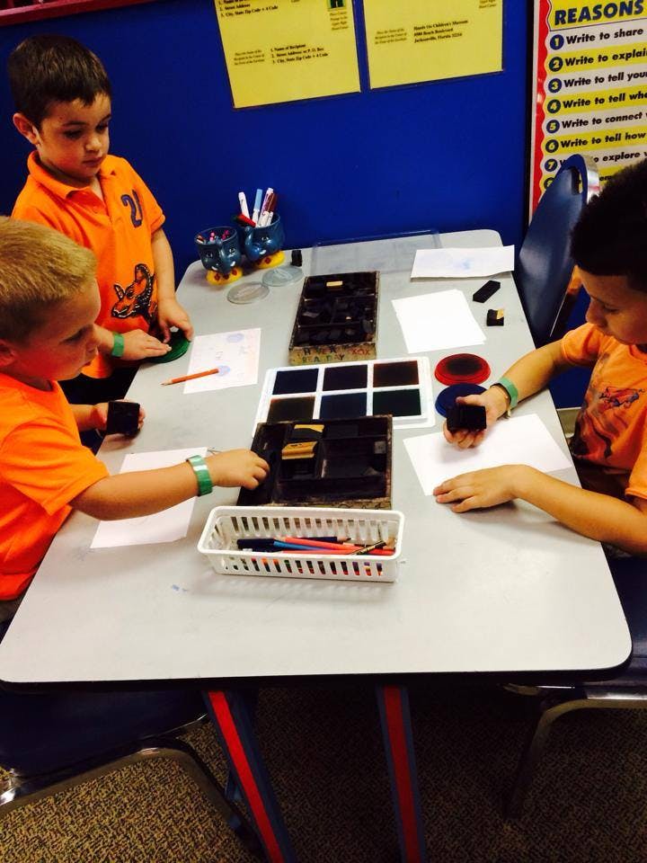 Three children at a table with art supplies