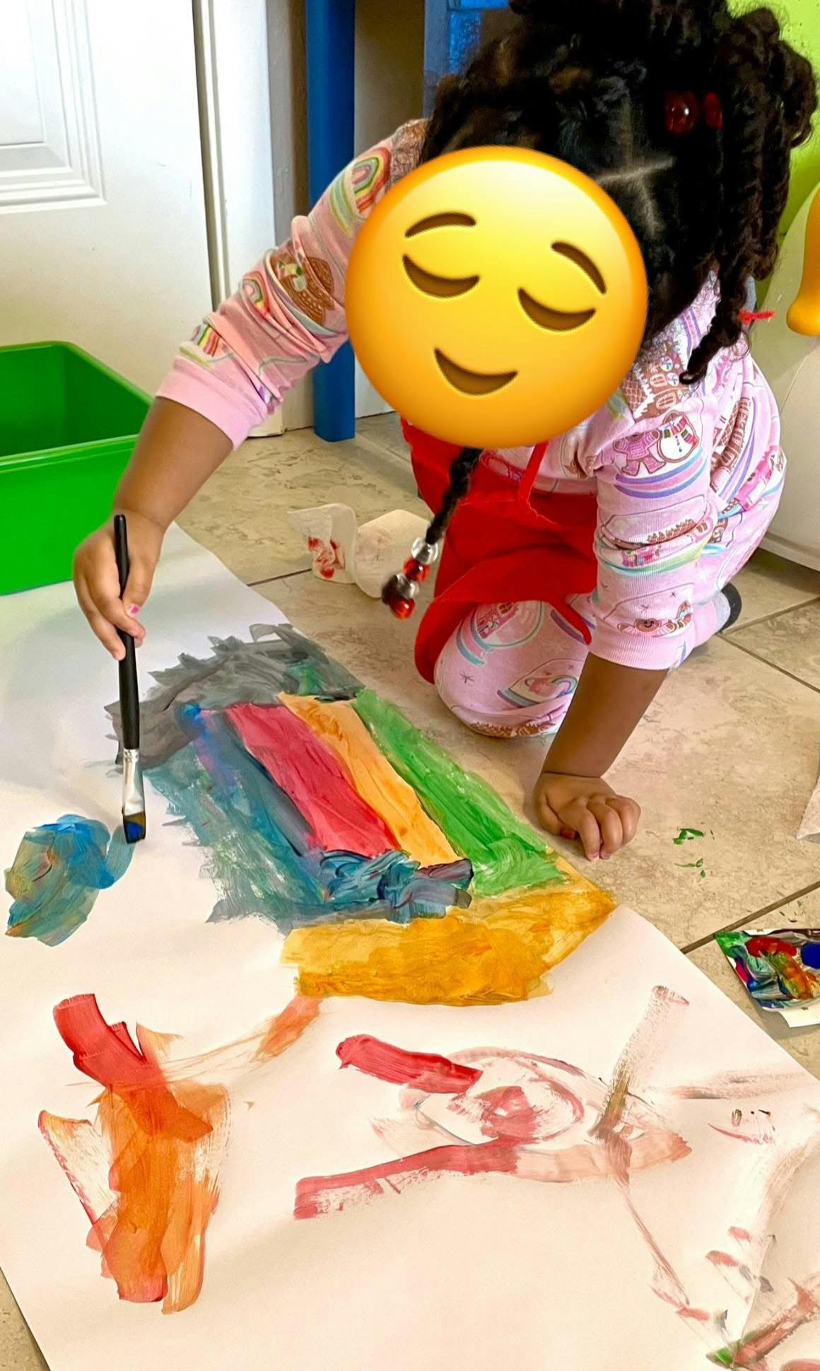 Child painting on large paper with a paintbrush