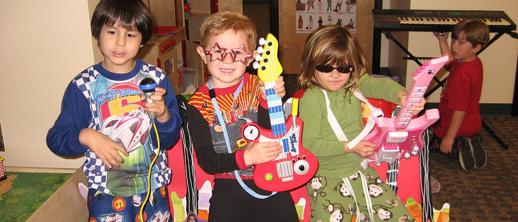 Three children playing with toy musical instruments